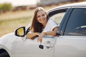Confident new driver smiling as she leans out of her car window